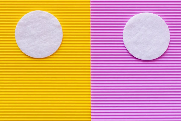 Top view of two cotton pads on purple and yellow textured background — Stock Photo