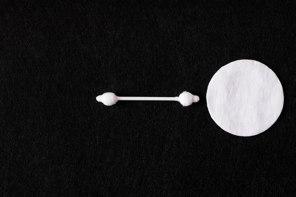 Top view of white cotton pad and ear stick on black background — Fotografia de Stock