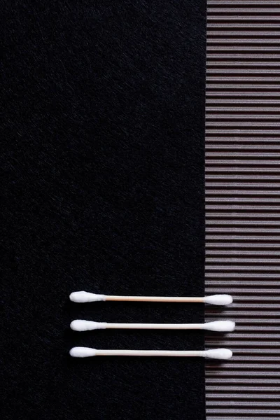 Top view of two cotton ear sticks on black and textured background with copy space — Fotografia de Stock