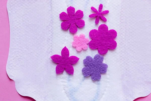 Top view of purple flowers on white breathable panty liner on violet background — Foto stock