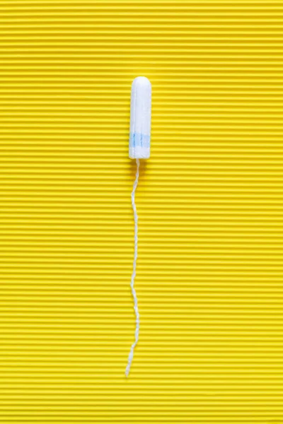 Vista superior do tampão higiênico sobre fundo texturizado amarelo brilhante — Fotografia de Stock