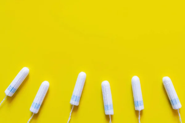 Top view of white cotton tampons on yellow background with copy space — стоковое фото