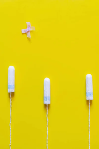 Top view of bow near hygienic tampons on bright yellow background - foto de stock