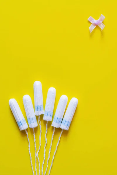 Top view of tampons and bow on yellow background with copy space — стоковое фото