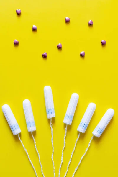 Top view of tampons near decorative hearts on yellow background — Foto stock