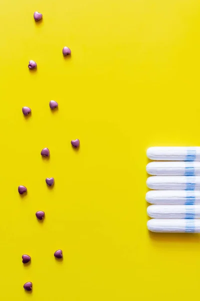 Vue du haut des cœurs décoratifs près de la rangée de tampons sur fond jaune — Photo de stock