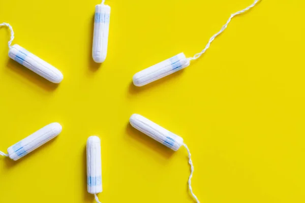 Circle of hygienic tampons on bright yellow background, top view — Photo de stock