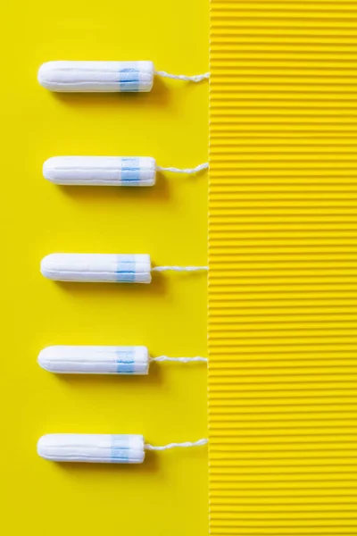 Top view of vertical row of tampons on yellow and textured background — Foto stock