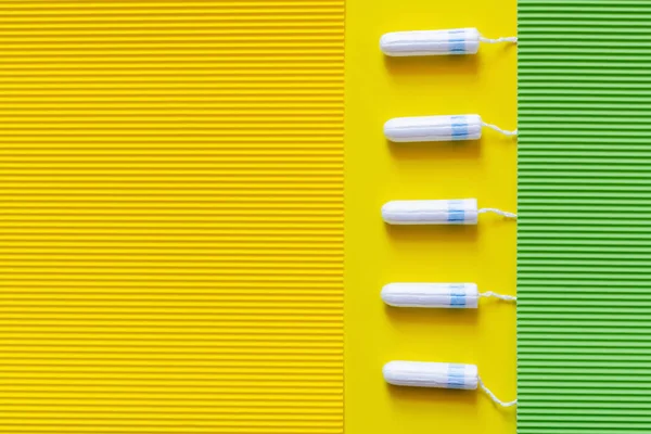 Vertical row of tampons on yellow and green textured background — Stock Photo