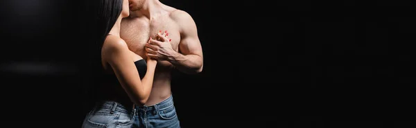 Cropped view of sexy woman touching shirtless man on black background, banner — Stock Photo