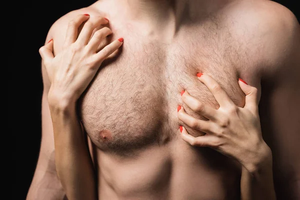 Cropped view of woman scratching chest of sexy man isolated on black - foto de stock
