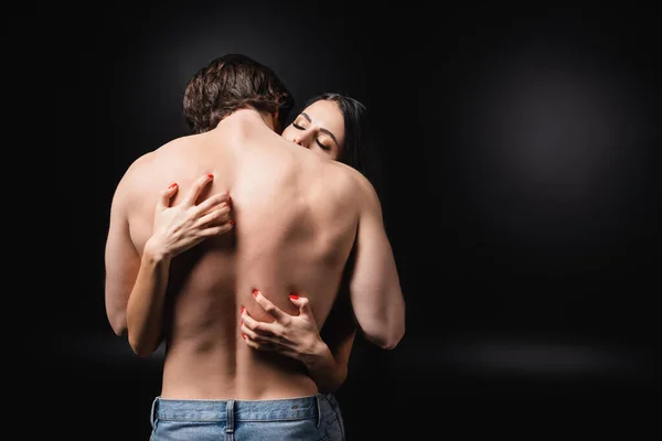 Young woman scratching back of sensual boyfriend on black background — Stockfoto