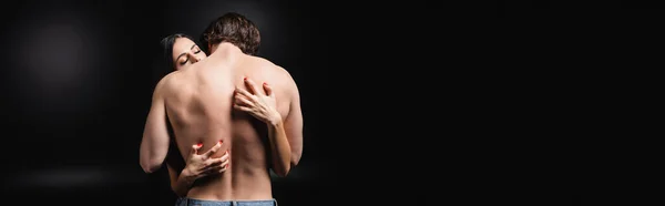 Appassionato donna graffiare indietro di uomo muscolare su sfondo nero, banner — Foto stock