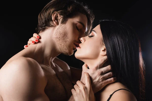 Side view of sexy couple kissing with closed eyes isolated on black — Fotografia de Stock