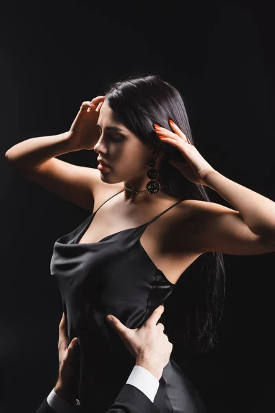 Man in formal wear touching waist of sensual girlfriend in dress isolated on black — Stock Photo