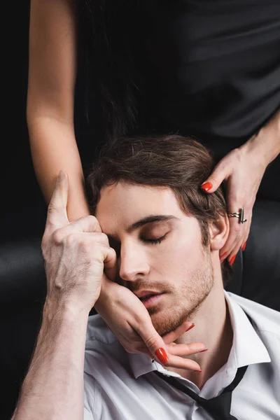 Jeune femme touchant le visage du petit ami en chemise et cravate isolé sur noir — Photo de stock