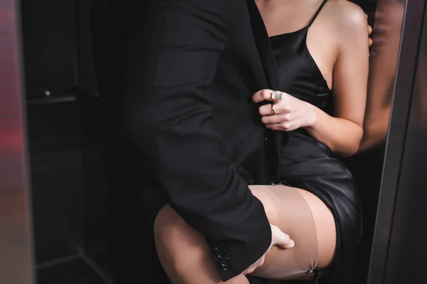 Cropped view of man in formal wear touching sexy woman near elevator — Photo de stock