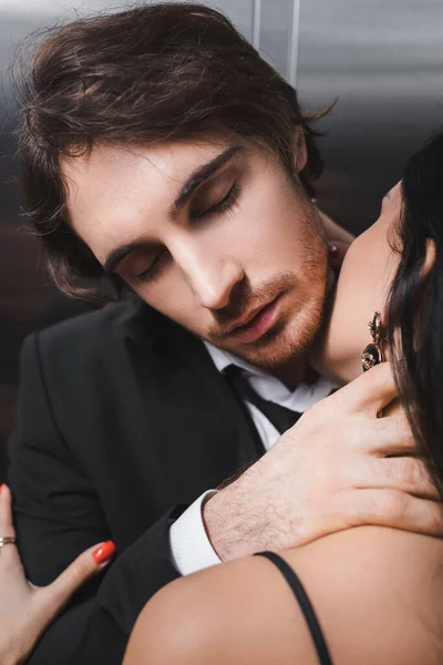 Brunette woman kissing young boyfriend in suit in elevator — стоковое фото