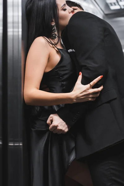 Man in suit taking off dress from sexy girlfriend in elevator — Stock Photo