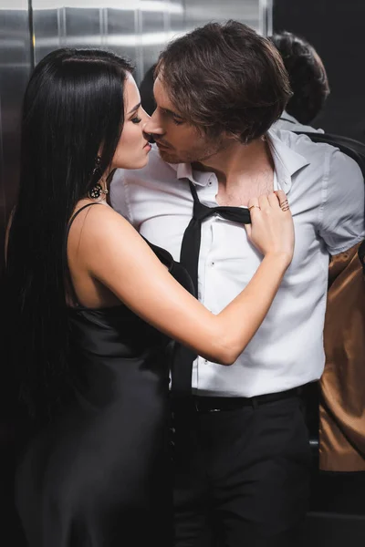 Sexy man taking off jacket and kissing girlfriend in elevator — стоковое фото