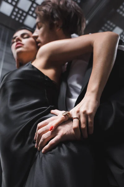 Low angle view of blurred man touching hip of sexy girlfriend in dress in elevator - foto de stock