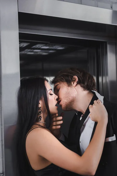 Sexy couple in formal wear kissing near elevator — Stock Photo
