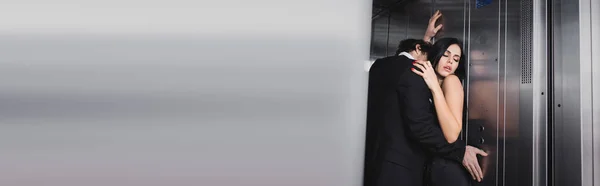 Man pressing button in elevator and kissing sexy girlfriend, banner — Stock Photo