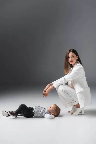 Femme en costume blanc regardant caméra près de fils couché sur gris — Photo de stock