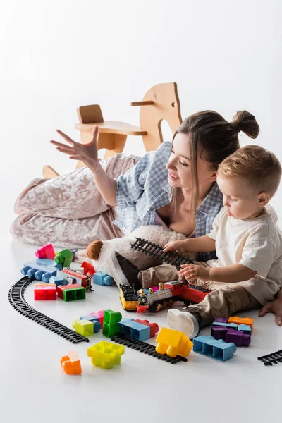 Jeune femme geste près de fils et jouets sur blanc — Photo de stock