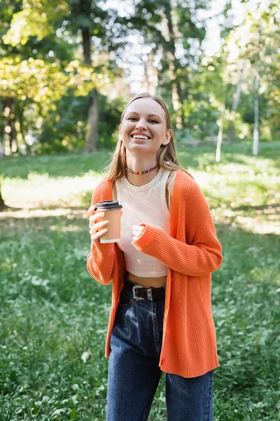 Весела жінка тримає паперову чашку з кавою, щоб піти — стокове фото