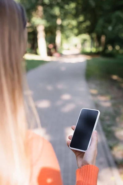 Back view of woman holding smartphone with blank screen — Stockfoto