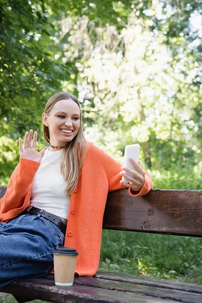 Glückliche Frau winkt bei Videoanruf auf Bank — Stockfoto