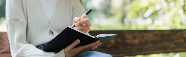 Ausgeschnittene Ansicht einer Frau, die in Notizbuch, Banner schreibt — Stockfoto