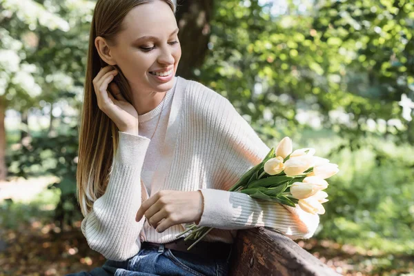 Fröhliche Frau mit blühenden Tulpen im grünen Park — Stockfoto