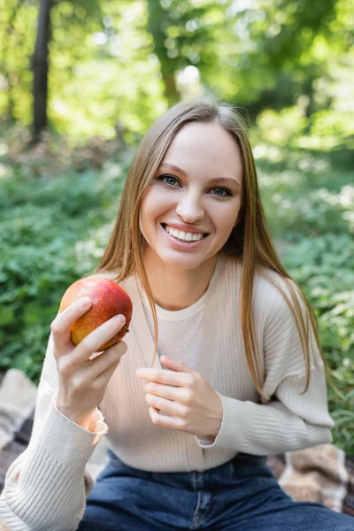 Щаслива жінка тримає червоне смачне яблуко в зеленому парку — стокове фото