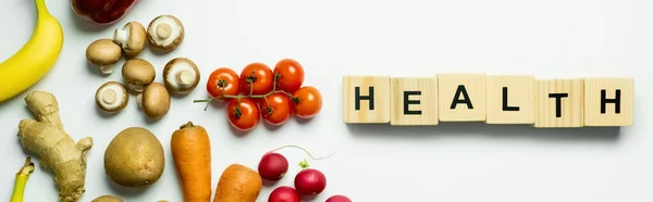 Top view of fresh food near cubes with health lettering on white background, banner — Stock Photo
