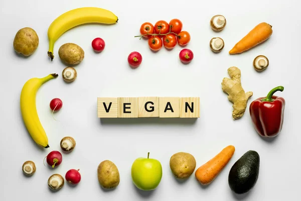 Draufsicht auf Würfel mit veganem Schriftzug und frischen Lebensmitteln auf weißem Hintergrund — Stockfoto