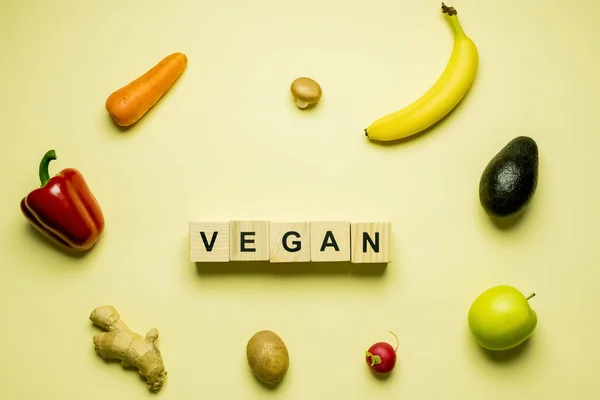 Draufsicht auf Würfel mit veganem Schriftzug in der Nähe frischer Lebensmittel auf gelbem Hintergrund — Stockfoto