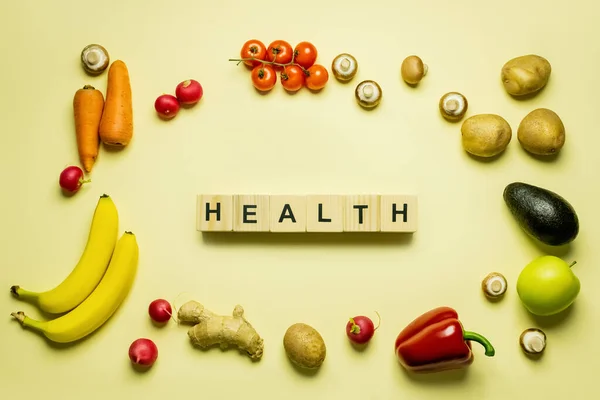 Top view of cubes with health lettering near organic food on yellow background — Fotografia de Stock