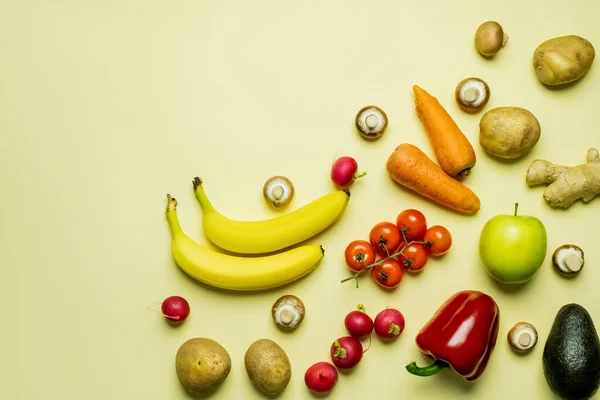 Colocación plana de frutas y verduras naturales sobre fondo amarillo - foto de stock