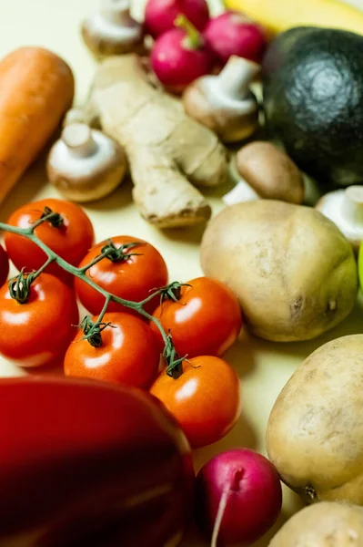 Vista de cerca de tomates cherry frescos cerca de verduras borrosas sobre fondo amarillo - foto de stock