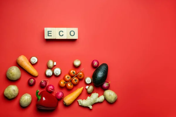 Ansicht von Bio-Gemüse in der Nähe von Öko-Schriftzug auf Würfeln auf rotem Hintergrund — Stockfoto