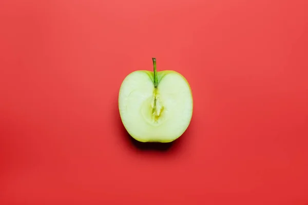 Vista superior de la mitad de manzana verde sobre fondo rojo - foto de stock