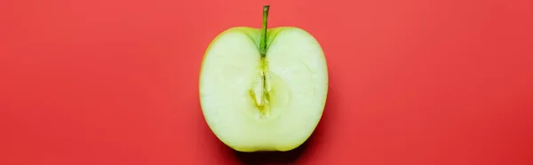 Top view of cut green apple on red background, banner — Stockfoto