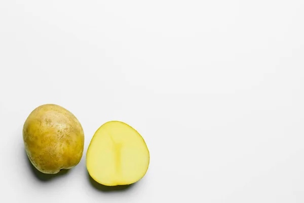 Vista superior de papas cortadas y enteras sobre fondo blanco - foto de stock