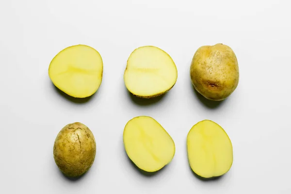 Flat lay with cut and whole potatoes on white background — Foto stock