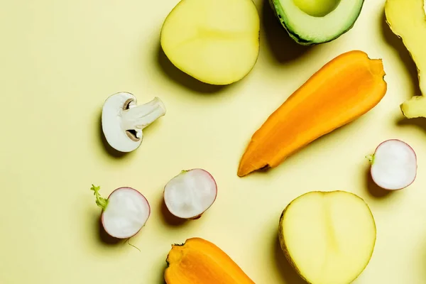 Top view of cut radish and carrot near fresh food on yellow background — Stockfoto