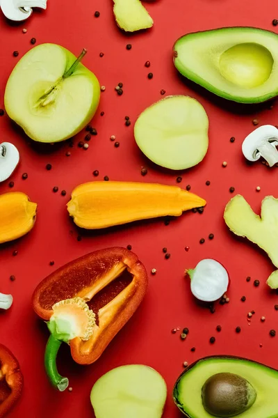 Vista superior de alimentos frescos cortados y granos de pimienta sobre fondo rojo - foto de stock