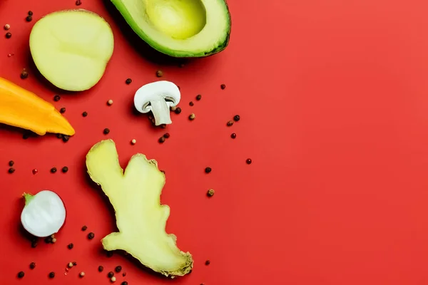 Top view of fresh ginger, cut avocado and peppercorns on red background — Stock Photo