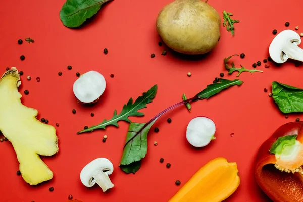Draufsicht auf Grün- und Pfefferkörner in der Nähe von geschnittenen Bio-Lebensmitteln auf rotem Hintergrund — Stockfoto
